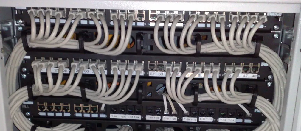 Stock photo: network patch panels in an equipment rack, with short gray cables looped neatly and held with cable ties.