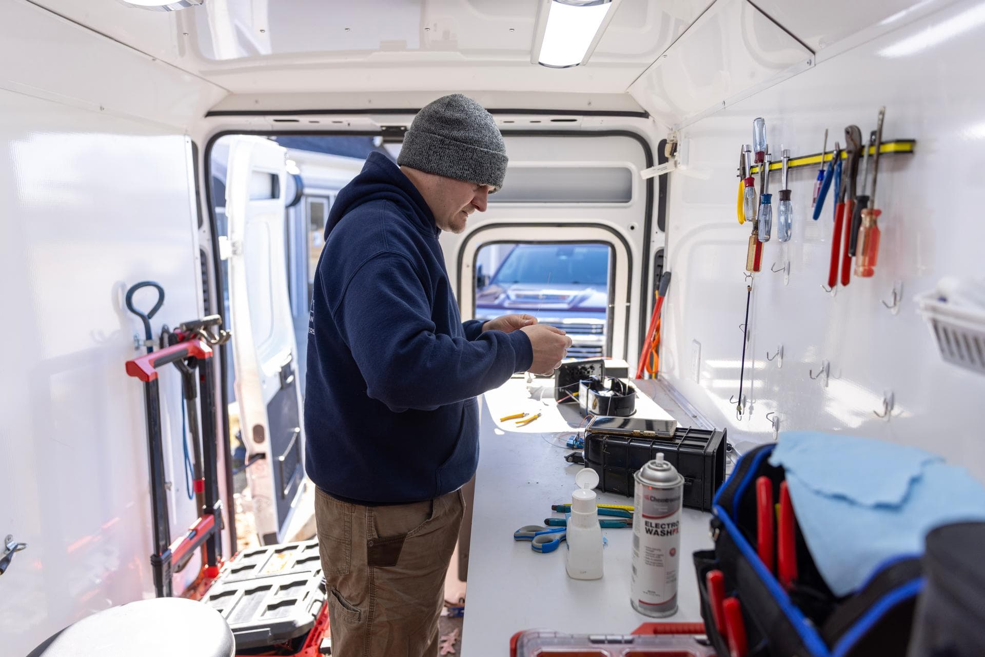 A Norvet MSP technician preparing fiber terminations at the workbench inside the service van on a job site