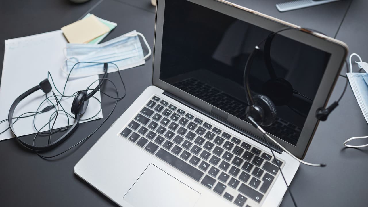 Stock photo: a headset resting beside an open laptop on an office desk.