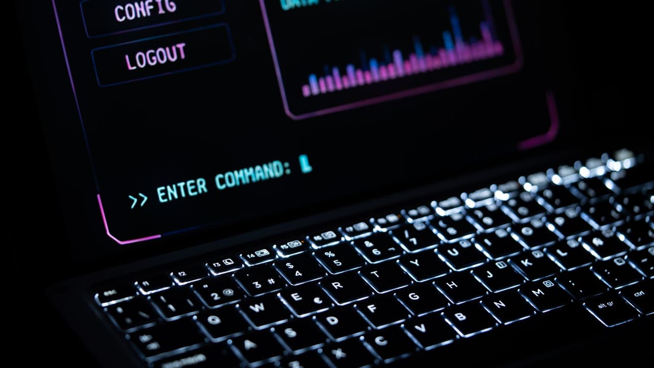 Stock photo: a laptop keyboard glowing in the dark below a command-line screen.