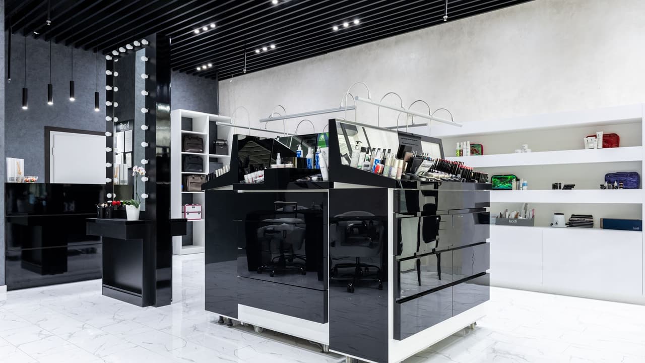 Stock photo: a modern cosmetics store with a black checkout counter and white display shelves.