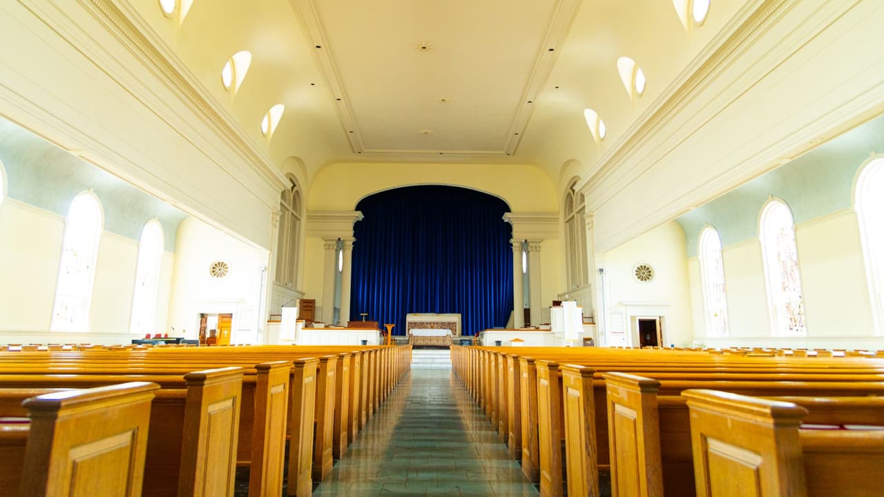Stock photo: the empty interior of a church with rows of pews facing the front.