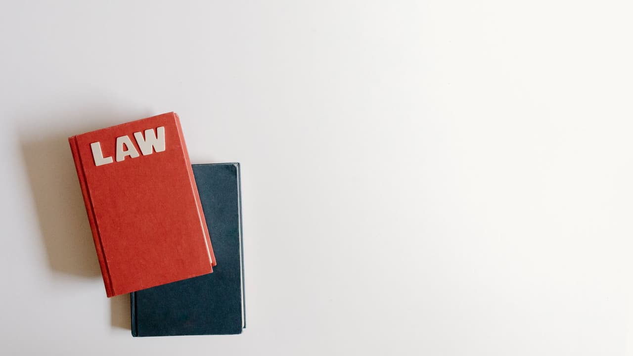 Stock photo: a red law book and a blue book lying flat on a white surface.