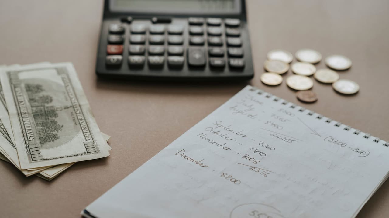 Stock photo: a calculator, cash and a notebook on a desk.
