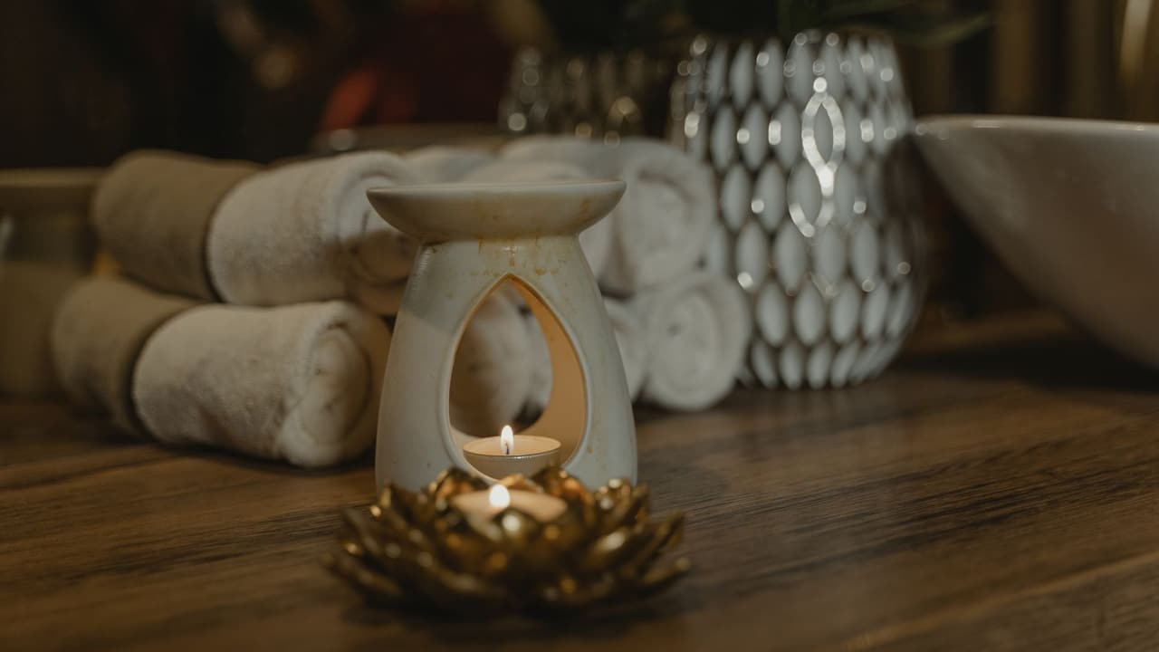 Stock photo: rolled towels, a candle and an oil burner in a calm spa setting.